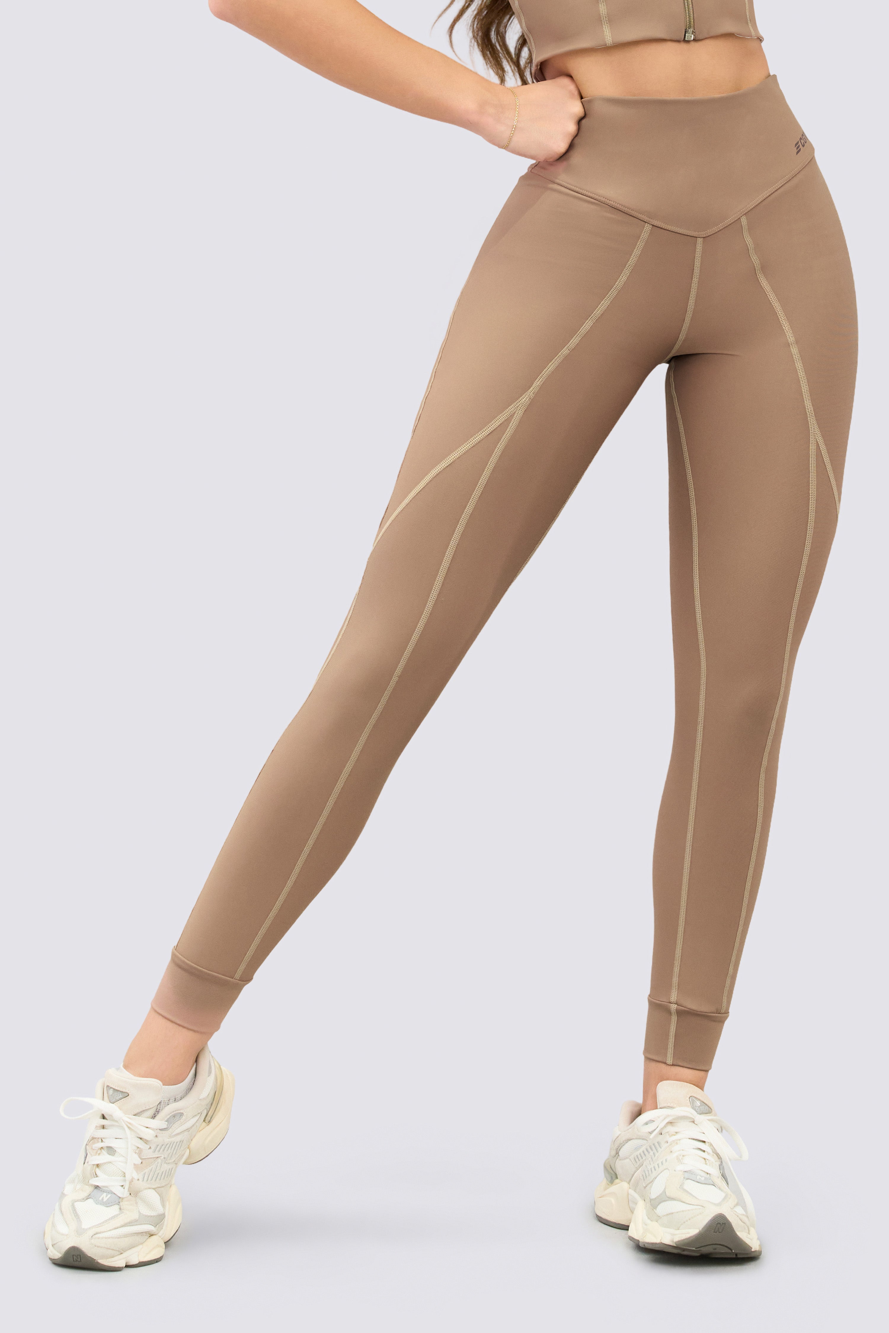 Mocha-colored sports leggings with a high waist and seams along the length of the garment that give them a dynamic look.