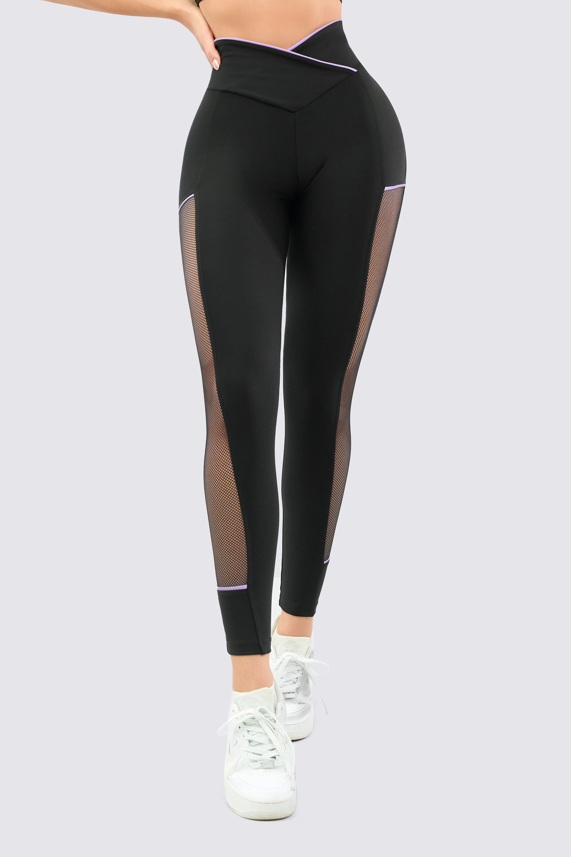 Black leggings, with high rise and mesh panels, and lilac stitching.