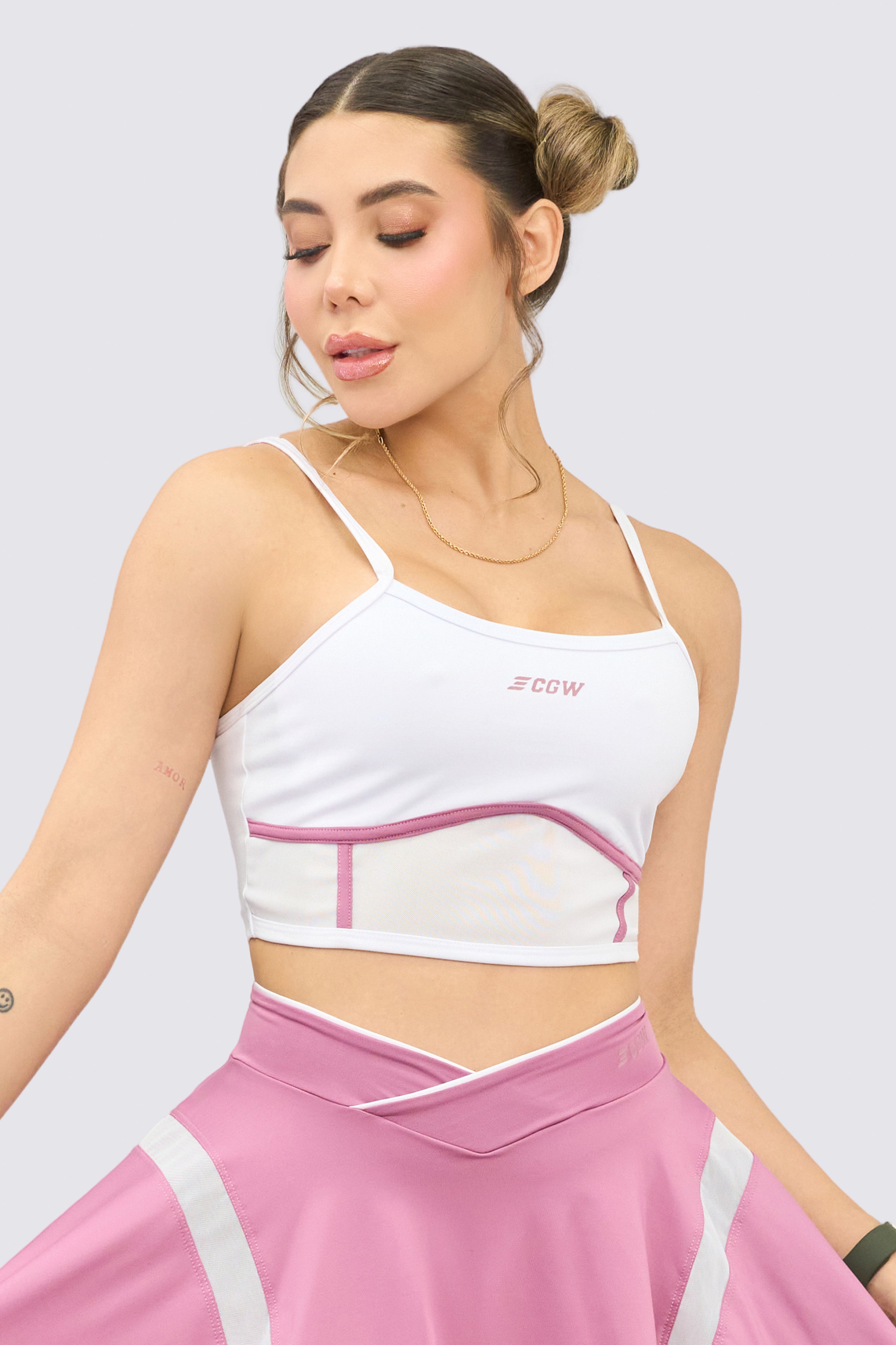 White sports top with thin straps, strategic front mesh, and pink stitching.